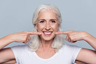 Older woman pointing to flawless smile