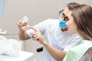 Dentist showing patient an implant denture model