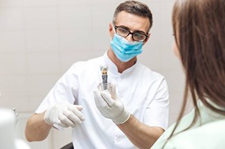 Dentist showing patient implant crown model