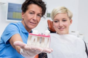 Dentist showing dental implant model to patient