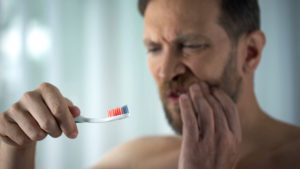 man brushing teeth gum pain