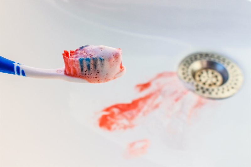 A toothbrush with blood on it and in the sink.